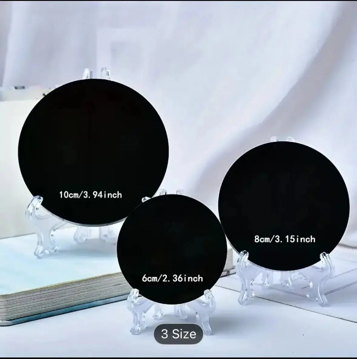 10cm Round Black Obsidian Mirror on a clear display stand for scrying and home energetic protection - Cosmic Blueprint 7 Australia